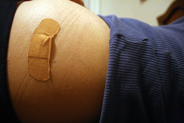 Nahaufnahme eines Verbandpflasters auf der Haut einer Person mit einem unscharfen Hintergrund.