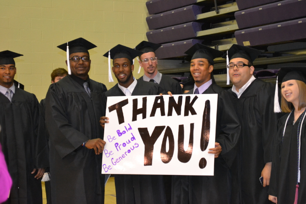 Eine Gruppe von Menschen, die in einer Reihe in der Mitte des Bildes stehen und jeweils ein Plakat mit der Aufschrift "danke" halten.