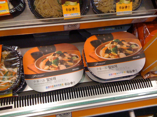 Lebensmittelkisten auf Regalen mit Preisaufklebern.