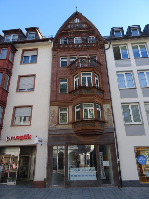 Zu verkaufendes Gewerbeobjekt in Heidelberg, Deutschland, mit einem mehrfenstrigen Gebäude an einer Straße mit einem klaren blauen Himmel im Hintergrund.