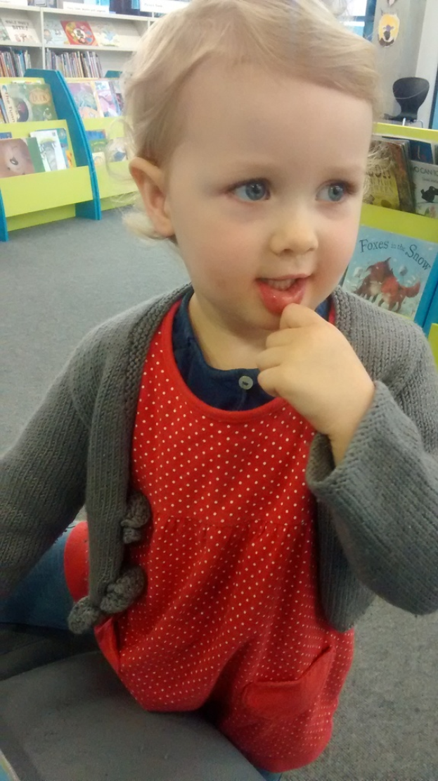 Ein kleiner Junge steht neben Regalen mit Büchern.