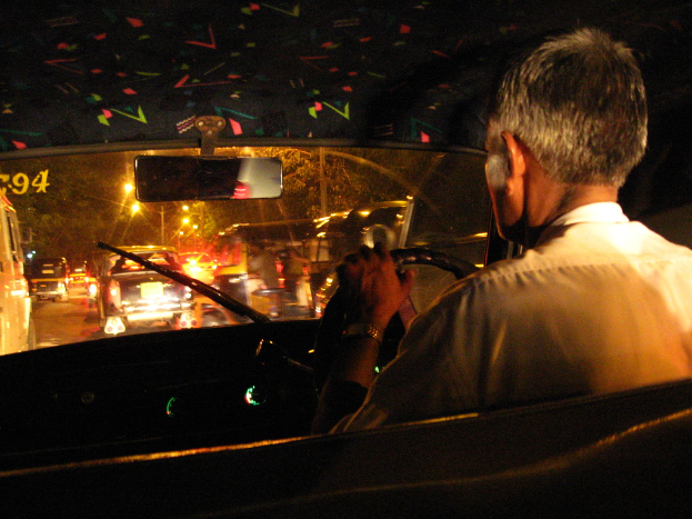 Eine Person wird beim Fahren eines Autos von innen gezeigt, wobei das Armaturenbrett und das Lenkrad zu sehen sind.