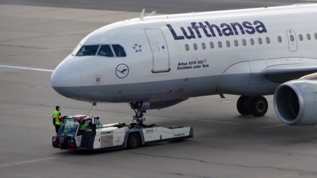 Ein Lufthansa Airbus A319-100 auf der Rollbahn am Frankfurter Flughafen, mit einem Fahrzeug und einer Person in der Nähe, bereit zum Start.