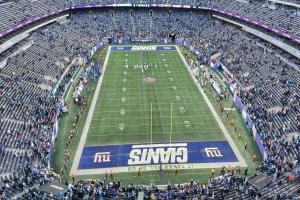 Ein Fußballstadion voller Zuschauer, Spieler und diverser Gegenstände auf dem Feld, einschließlich Tafeln mit Text und Sitzreihen.