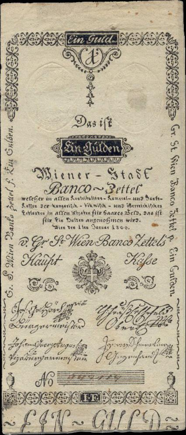 Eine alte deutsche Banknote mit schwarzem Hintergrund, die ein Männergesicht und den Text "St. Wien - Stäse Banco-Settel" zeigt.