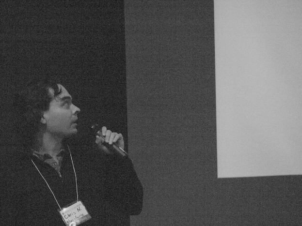 Eine Person, die ein Mikrofon hält und eine Anstecknadel trägt.