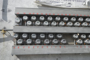 Nahaufnahme eines Elektrizitätszählers, der an der Seite eines Gebäudes montiert ist und ein Banner mit Text an der Spitze zeigt.