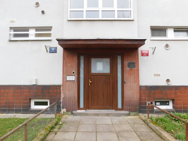 Zweizimmer-Terrassenhaus mit weißer Fassade, brauner Tür und Fenstern, Metallzaun, Gras, Weg und Brettern an der Wand, gelegen in St Johns Court, St Johns Road, Luton.