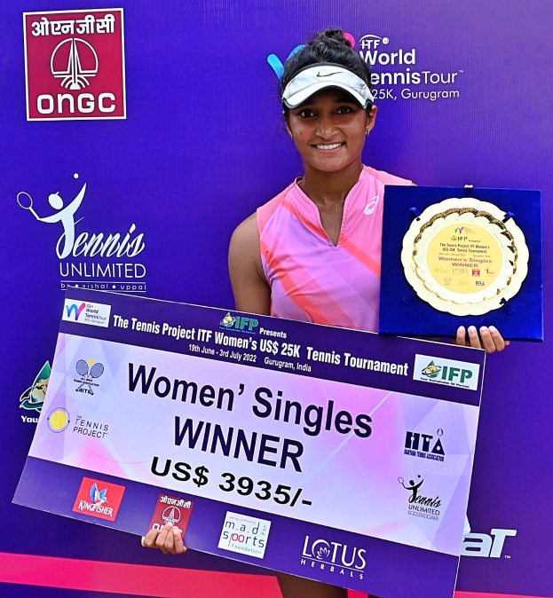Eine Frau auf einem Tennisplatz, die eine Trophäe und eine Tafel mit der Aufschrift "Frauen-Einzel-Siegerin" hält und eine Mütze mit einem Banner im Hintergrund trägt.