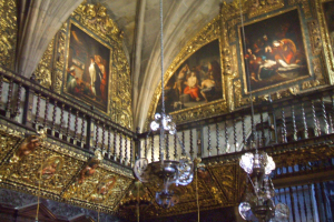 Ein prunkvoller Raum mit einem Kronleuchter, einem Geländer und mehreren Fotorahmen an den Wänden, der Eleganz und Opulenz ausstrahlt.