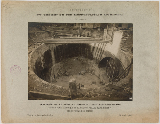 Ein altes Schwarz-Weiß-Foto eines Tunnels im Bau, mit einem Stempel auf der linken Seite und Text unten.