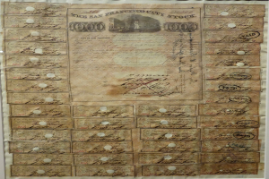 Ein altes Aktienzertifikat mit zahlreichen Unterschriften, Texten und Zahlen darauf.