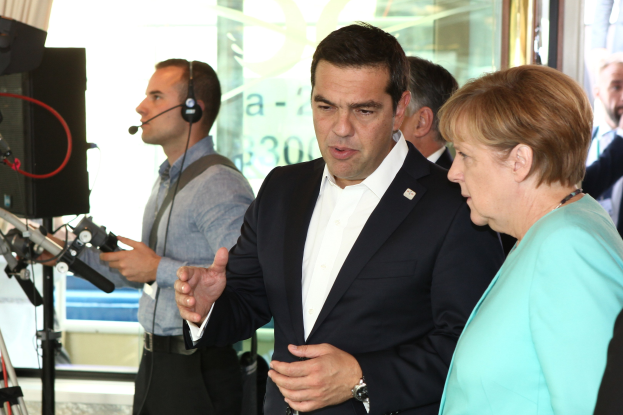 Die beiden deutschen Bundeskanzlerinnen Angela Merkel und Joachim Gauck stehen vor einer Glaswand mit einem Vorhang dahinter und sprechen in Mikrofone, während sie Anzüge tragen.